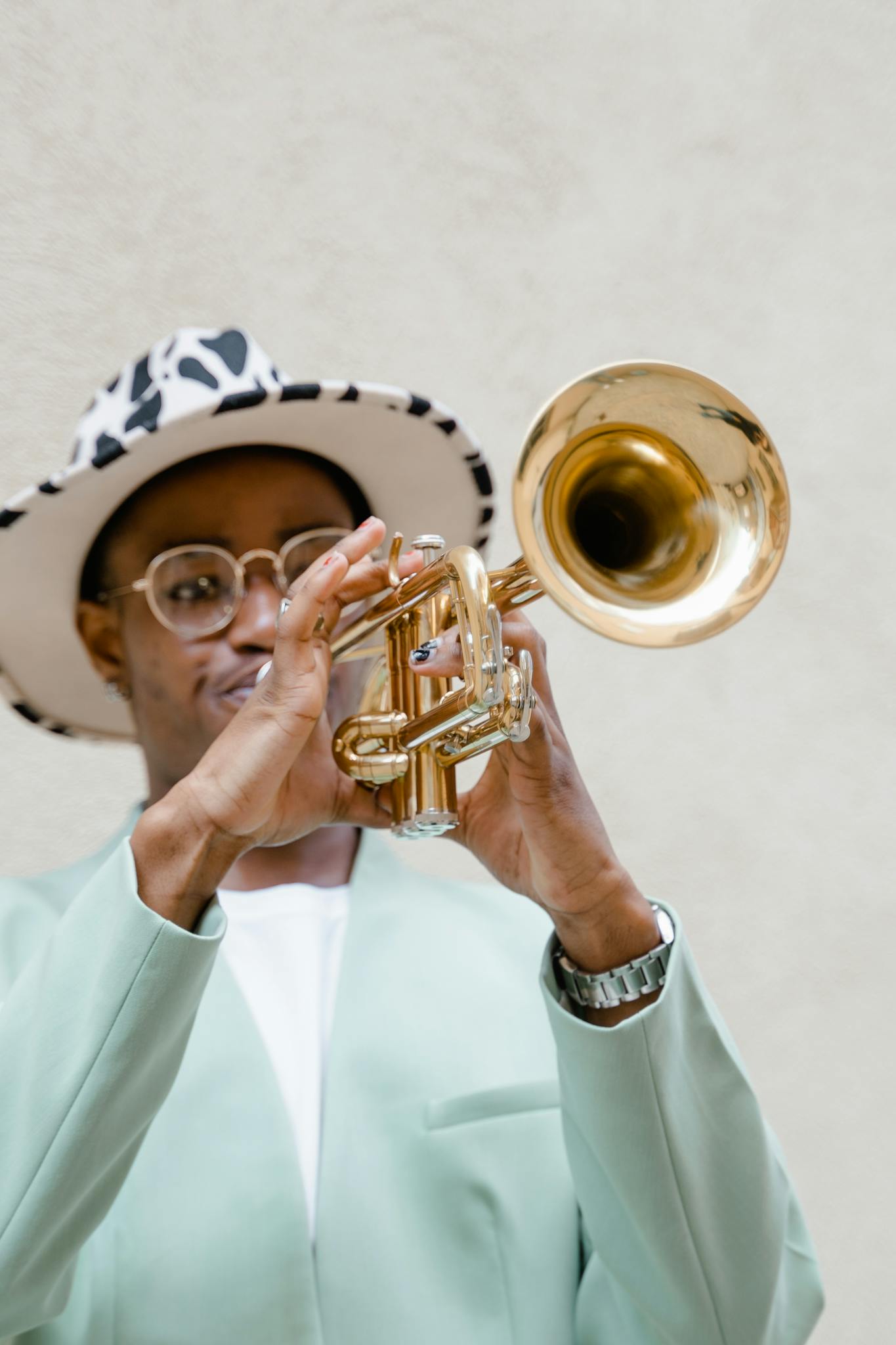 A stylish man plays a trumpet outdoors, showcasing vibrant street music culture.